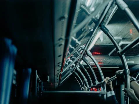Crowded public bus interior with hanging handles and night city lights 스톡 사진