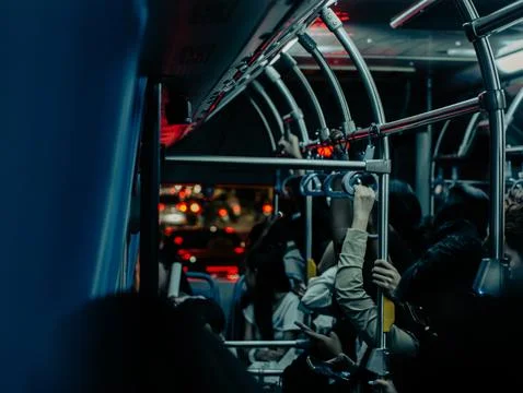 Crowded public bus interior with hanging handles and night city lights Photos