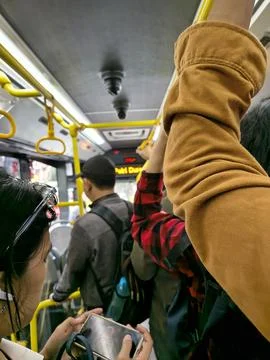 Crowded public bus interior with standing passengers holding handles. Stock-Fotos
