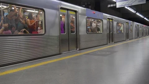  A crowded silver subway train stopped at an underground station platform Stock Footage 338185503