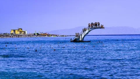 A crowded white dive platform in the middle of the blue sea at Rhodes island Stock Photos
