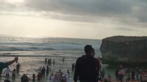 Crowded Yogyakarta Beach Sunset with Cliffs and Vendors Stock Footage 319926309