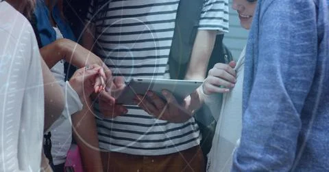 Crowding five peers around tablet at school hallway, striped shirt holder Stock Photos