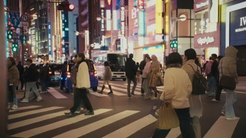 Crowds Cross a Busy Intersection Amid Neon Signs in Ginza, Tokyo Stock Footage 345376559