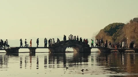 Crowds Crossing a Stone Arch Bridge at West Lake in Hangzhou Stockbeeldmateriaal 347713680