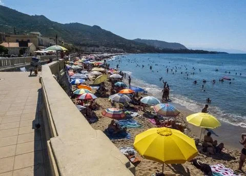 Crowds fill Cefal's sandy beach and shallow blue water Stock Photos