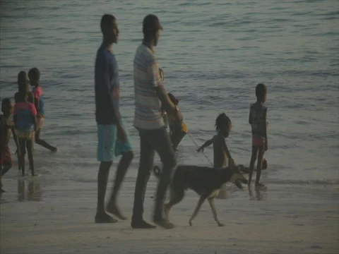 Crowds of locals walk down the beach, as children play on the coast of Kenya. Stock Footage 85012778