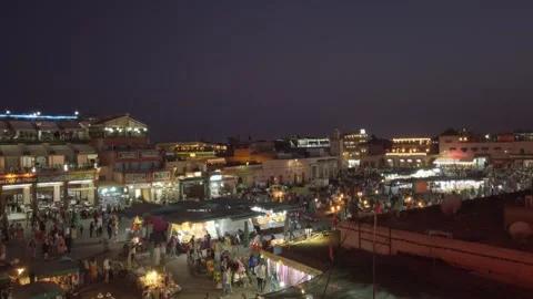 Crowds move through Marrakesh's illuminated Jemaa el-Fnaa market at night Stock Footage 336757367