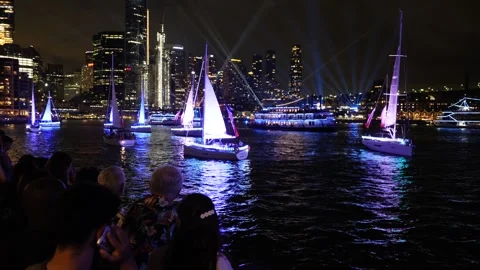 Crowds at night watch neon sailing boats and Sydney skyscrapers on Aus Day Stock Footage 330458337