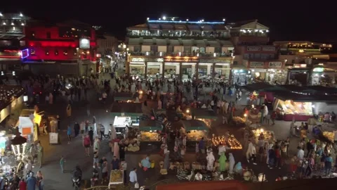Crowds pass through Jemaa el-Fnaa stalls under an evening glow in Marrakesh Stock Footage 336757159