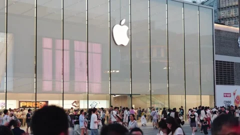 Crowds of people move past a large Apple Store with a prominent logo on a busy Stock Footage 339329579