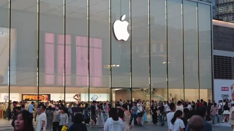 Crowds of people move past a large Apple Store with a prominent logo on a busy Stock Footage 339329582