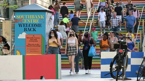 Crowds of people, some wearing face masks, walk up and down colourful stairs Stock Footage 159235222