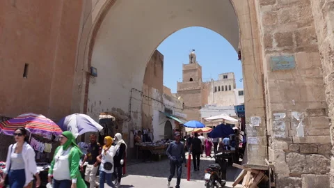 Crowds of people walk to entry gate medina Sfax, history economy Tunisia Stock Footage 319849587