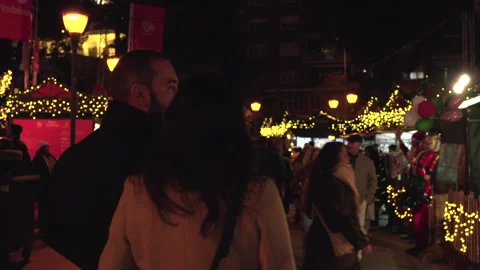 Crowds strolling through an illuminated Christmas market at night 스톡 동영상 323296223