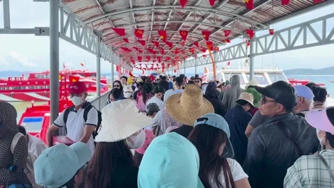 Crowds of tourists lining up under a sheltered pier to board high speed boats Stock Footage 327802456