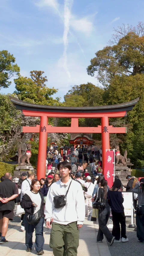 Crowds of Tourists Walking Through Large Red Torii Gate in Kyoto Stock Footage 337689762