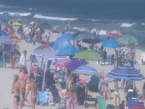 CROWED BEACH IN THE SUMMERTIME WITH UMBRELLAS Stock Footage 76618652