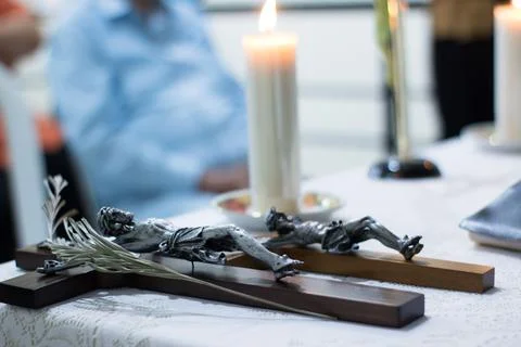 Crucifix Statue of Jesus Lying on Table Beside Candle in Religious Setting 스톡 사진