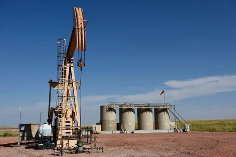 Crude oil well site pump jack and production storage tanks Stock Photos