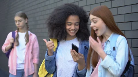 Cruel teenagers bullying female classmate by smartphone, cyber abuse, conflict Stock Footage