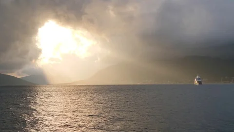 Cruise ship floats in rays of sunset light shining through break in stormy 動画素材 83122901