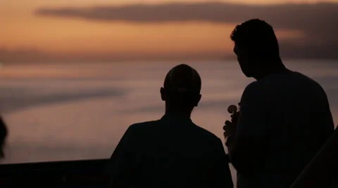 Cruise ship passengers in silhouette point to location in distance during sunset Stock Footage