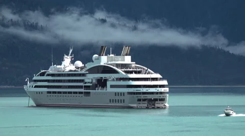 Cruise Ship Sitting in Emerald Water As Boat Passes Stock Footage