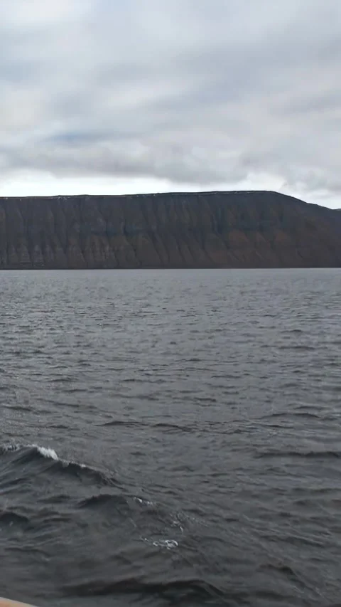Cruising Arctic Waters by Dramatic Mountain Walls Under Cloudy Skies 스톡 동영상 344316198