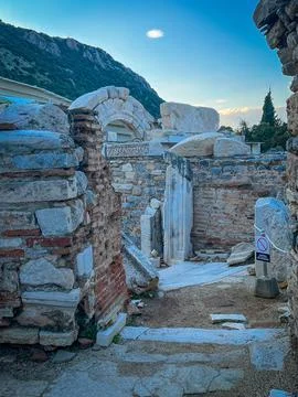 Crumbling Archway Frames Mountain Peaks under Crescent Moon Glow Фото
