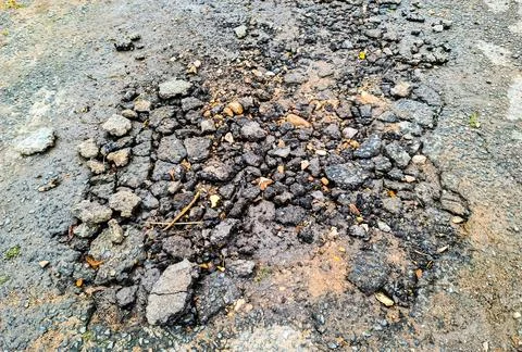 Crumbling asphalt road surface indicating damage and decay Stock Photos