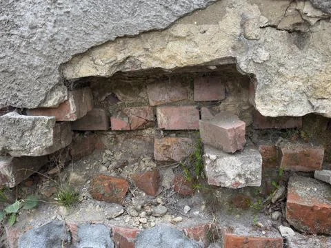Crumbling brick wall exposed through broken plaster with weeds growing thro.. Stock Photos