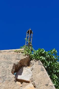 Crumbling wall of an old structure with an iron fence post on top. Stock Photos