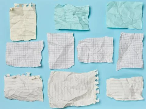 Crumpled and torn squared and lined paper sheets laid out on a blue backgroun Stock Photos
