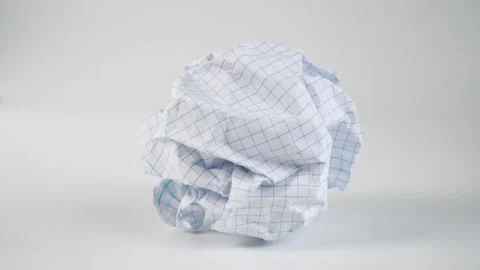 A crumpled ball of empty squared paper sheet falls on the white surface of th Stock Footage 155253303