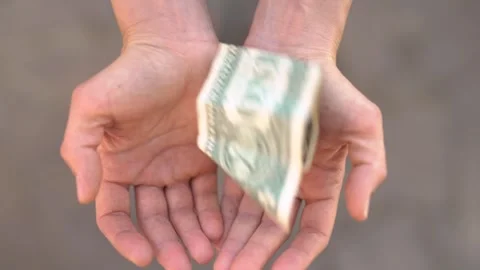 Crumpled banknote falls into open palms Stock Footage 266913437