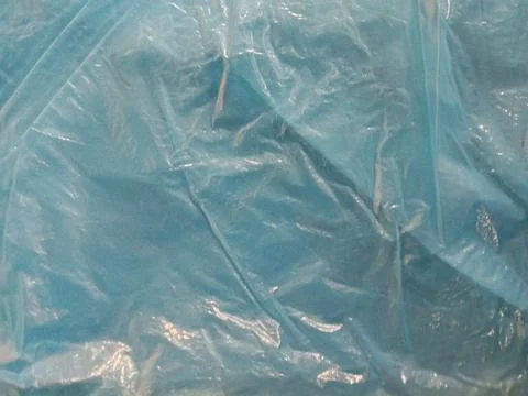 Crumpled blue plastic sheet texture background with light reflections Stock Photos