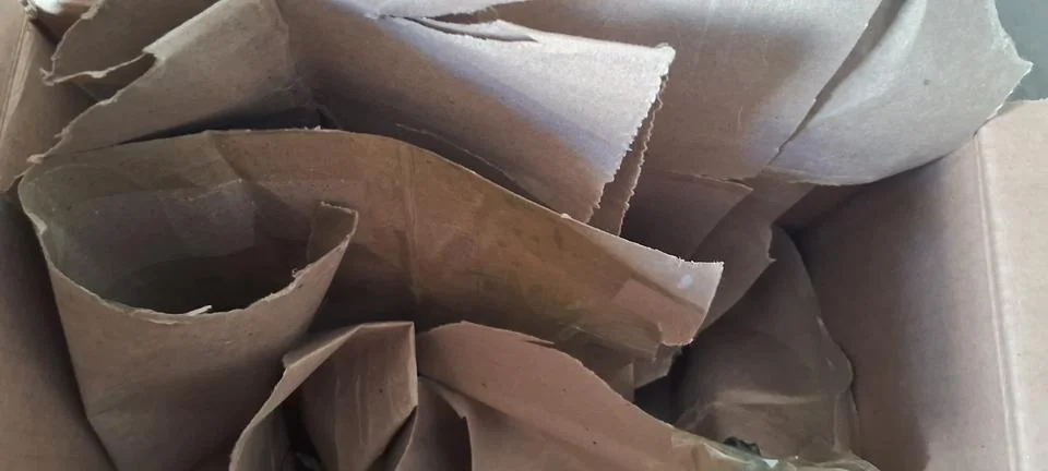Crumpled brown paper sheets inside a deep cardboard shipping box Stock Photos