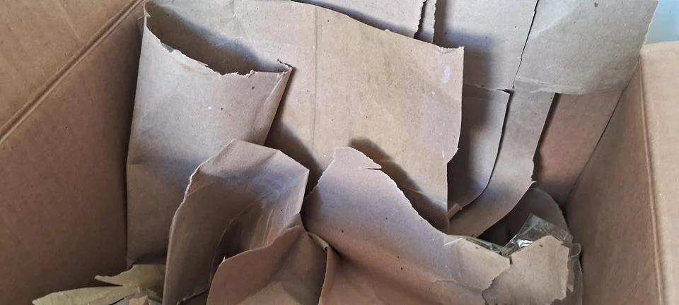 Crumpled brown paper sheets inside a large cardboard shipping box Stock Photos