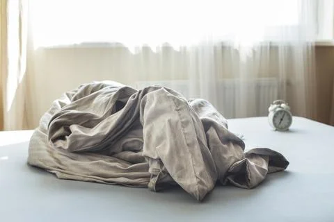 Crumpled empty bed in a room on a window background. Weekend morning. messy b 스톡 사진