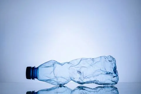Crumpled empty clear plastic bottle on blue Stock-Fotos