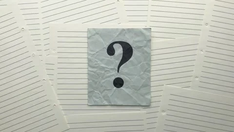 Crumpled gray paper note with question mark on it lying on lined notebook pages. Stock Footage 313344669