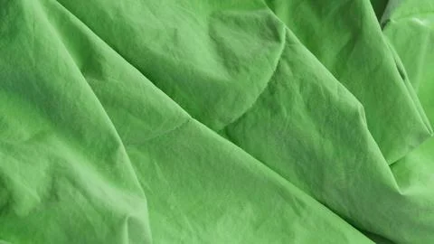 Crumpled green fabric featuring a subtle textured feather pattern. Stock Photos
