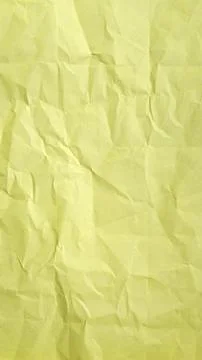 Crumpled light yellow paper texture background with deep creases and folds. Stock Photos