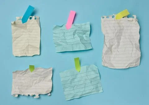 Crumpled lined paper sheets secured with multicolored sticky notes on a blu.. Stock Photos