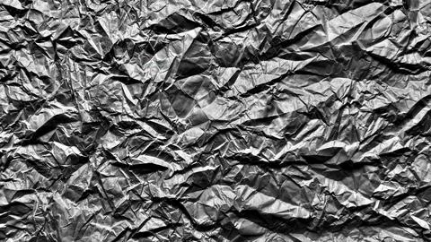 Crumpled metallic foil texture forms dramatic abstract monochrome pattern c.. Stock Photos