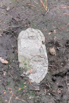 Crumpled old plastic bottle lying in the mud Stock Photos