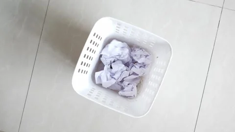 Crumpled paper ball falling into white trash bin placed on light tile floor.. 스톡 동영상 332879615