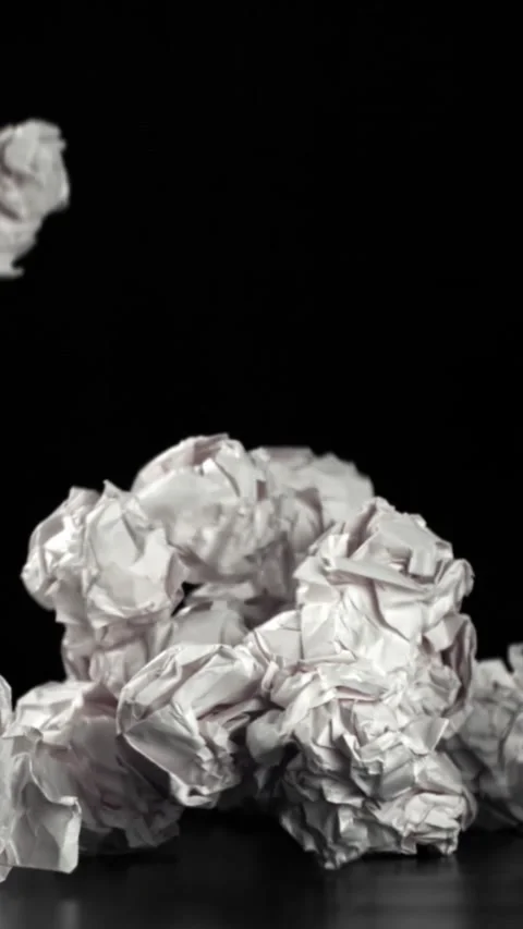 Crumpled paper falls on a black background. Filmed on a high-speed camera at Stock Footage 335367139
