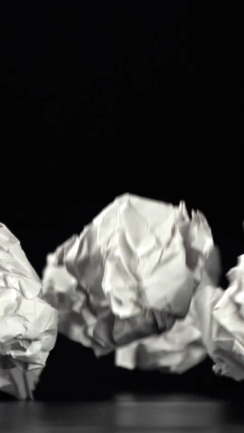 Crumpled paper falls on a black background. Filmed on a high-speed camera at Stock Footage 335370201